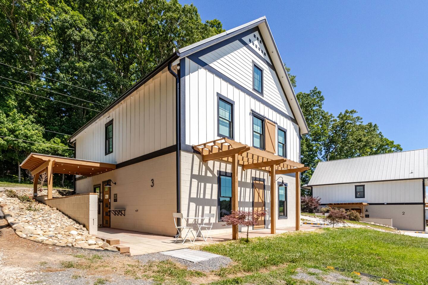 Modern farmhouse exterior with patio seating and peaceful wooded setting