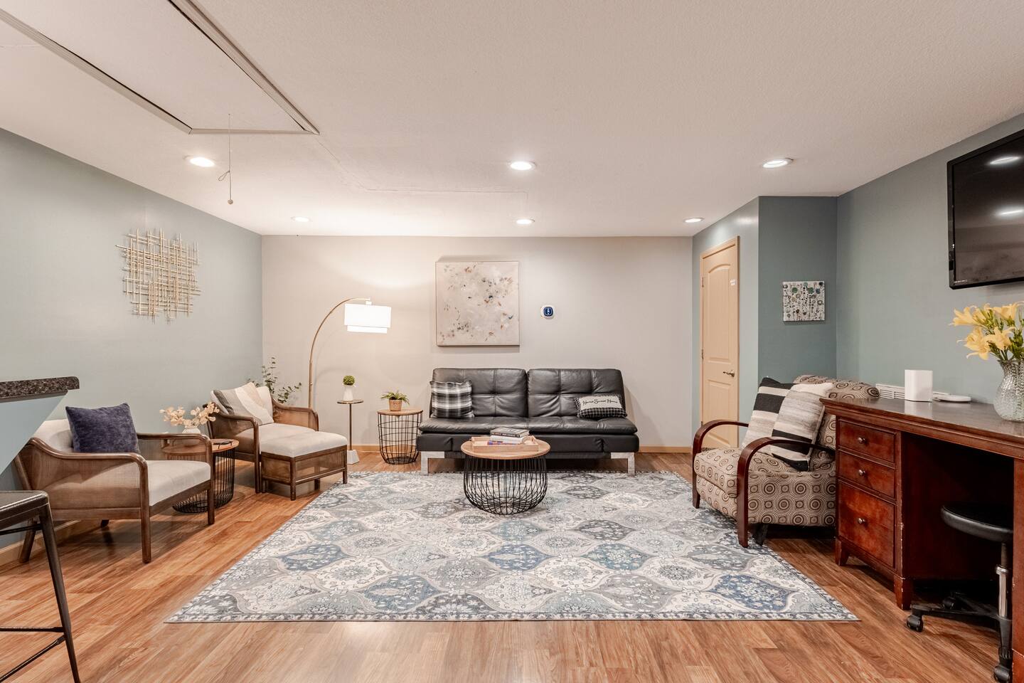 Spacious, cozy lounge with stylish seating, desk, and TV